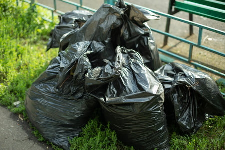 Garbage bags on the street. Black plastic bags for waste collection in the city. The result of cleaning in the yard bags with garbage.の写真素材