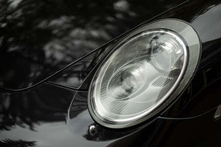 Car headlight. Black car with white headlight. Vehicle body parts. Machine lights.の写真素材