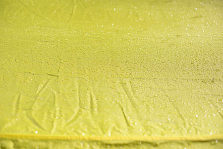 Wet cloth. Drops on yellow fabric. Wet awning from the rain.の写真素材