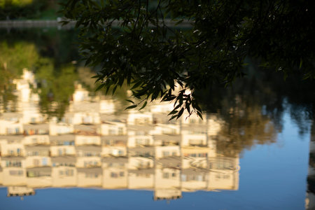The building is reflected in the water. The surface of the lake in the park. The white building is reflected as in a mirror. In summer in the park.の写真素材