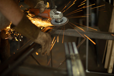 Work grinding machine. Sparks from the force of friction. A man in a workshop processes metal. Creation of a steel part.の写真素材