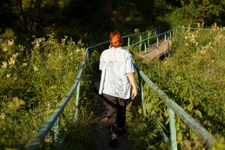 The girl goes to the forest. Walk in the park. A woman walks among the plants in summer. The schoolgirl is alone on the park path.の写真素材