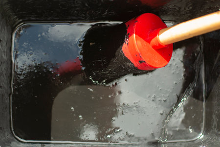 Brush in black paint. Brush in a container with waterproof paint. A tool for staining the surface. Thick paint in a jar.の写真素材