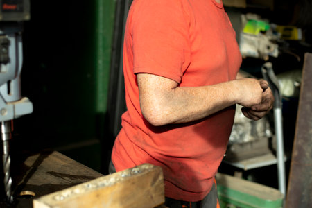 A worker in a red T-shirt behind the machine. Side view, dirty hands. Indoor work. Sunlight. City Lifestyleの写真素材