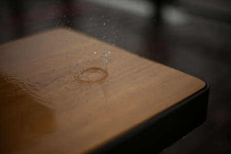 Raindrops break on the surface of the bench. Rain outside in detail. Small splashes of water.の写真素材