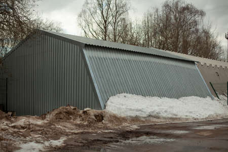 Metal warehouse outside. Storage room for municipal equipment. Snow covered the building.の写真素材