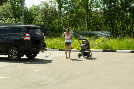 A girl with a stroller in the parking lot. A woman rests near the car. A person after a long trip...