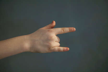 Child's hand shows gesture. Child's fingers. Hand on gray background.の写真素材