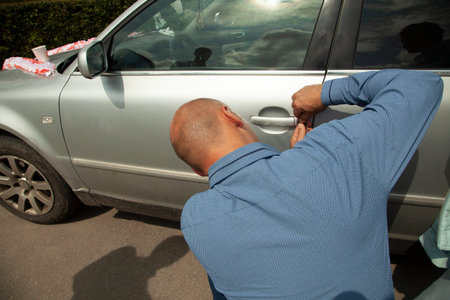 The man opens the car door. The guy lost his car key. A man tries to open a vehicle.