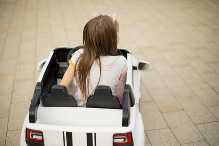 A child in a children's car. A girl in an electric car. Amusement park. The girl drives the transport.の写真素材