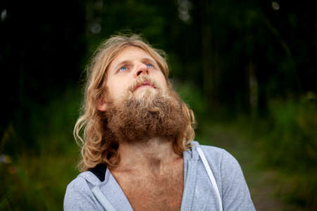 Guy with thick unshaved beard. Young man in white hoodie. man in nature. portrait of traveller.の写真素材
