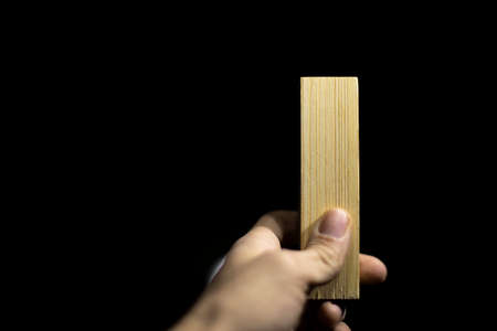 board in hand. Bar made of wood. Blank in hand of carpenter. Guy holds untreated board.の写真素材