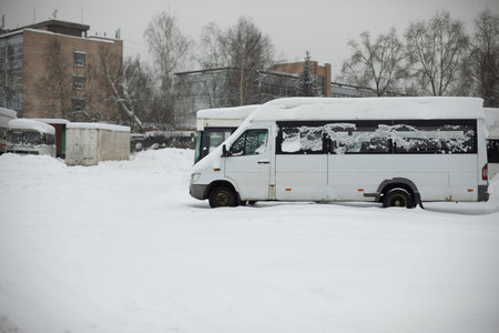 Buses in winter. Bus station in snow. White cars in parking lot. public transport.