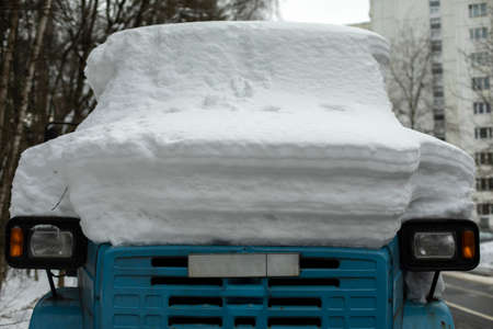 Hill of snow on car. Transport in winter. Truck in snowstorm. Car in parking lot.の写真素材