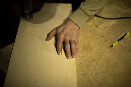 Carpenter holds tree. Worker chooses board. Details of carpentry workshop. Hand of woodworking master.の写真素材