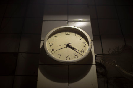 clock on wall. Round dial. Hands of clock. Time in room.
