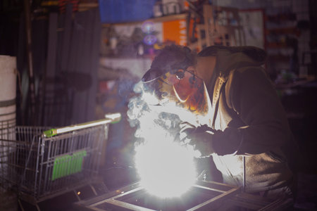 metal welding. Work in workshop. Welder creates seam. steel connection. Guy in garage. high fever....