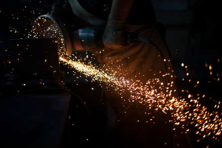 Work as grinder in workshop. metal grinding. Sparks from high temperature. Process of cutting steel profile.の写真素材