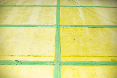 Yellow cells and green lines. Wall is painted. Structure is made of rectangles. Texture of building.