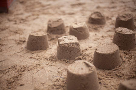 Sand cakes in sandbox. Lot of objects made from stove. Result of children's play. Children's playground in detail.の写真素材