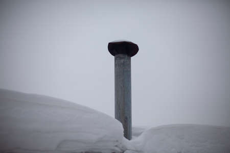 Chimney on the roof. Stainless steel heat dissipation pipe. Chimney from furnace. Snowy weather outside.の写真素材