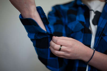 Girl fastens buttons on her shirt. Cozy plain shirt. clothes for home. Woman thinks what to wear. household details. blue shirt. Man's clothes on student.の写真素材
