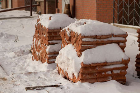 Bricks in winter. building material. Lots of bricks near house. Details of construction of house.の写真素材