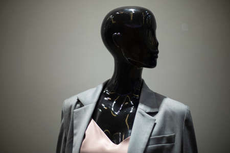 Mannequin is black. Figure of woman in jacket. Window of clothes store. black head.の写真素材