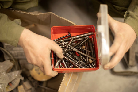 Drill bits in box. Hand holds box of drills. Tools in garage. production details.の写真素材