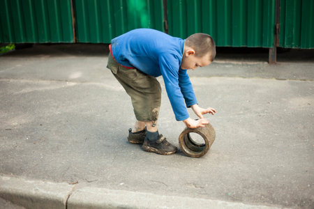 Child is holding dirty object. Little boy plays with concrete ring. child found thing. Baby's adventure in summer.の写真素材