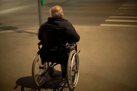 Wheelchair accessible at night. Man in wheelchair for disabled on road. Accessible environment in city. Persons with disabilities. medical chair.の写真素材