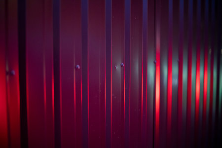 Purple light on fence. Steel profile in bright light. Fence in detail. Red glow on steel ribs.の写真素材
