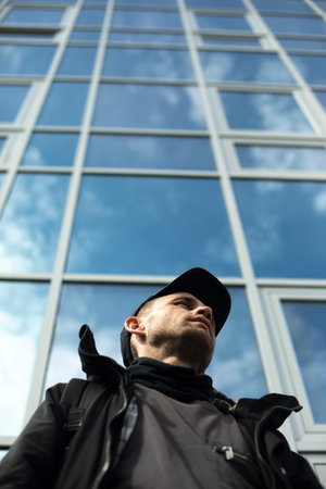 Guy in the background of glass building. man in cap. man in town.の写真素材