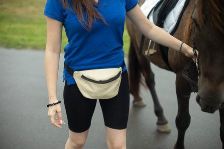 girl holding horse. Belt bag. Blue t-shirt. holding horse. young rider.の写真素材
