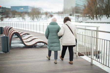 Girls walk in park in winter. Girlfriends on the street. people in the city. Two girls walk along the promenade.の写真素材