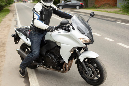 Motorcyclist takes to road. Biker on track. white motorcycle. Details of trip in helmet.
