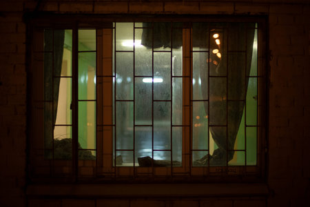 Window in building in the evening. Grille on window at night. Details of building.