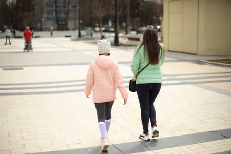 two girls walk through the square. Mother and daughter on the street. Walking outside in summer. people in metropolis.の写真素材