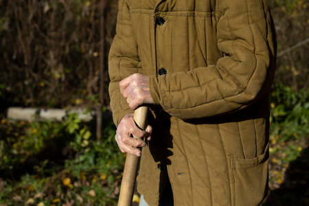 Old man's hands. old man holding stick. Poor clothes. Elderly person works on land. Male 92 years old.の写真素材