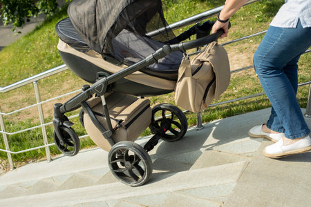 Descent of baby stroller on stairs. Woman lowers stroller with child. Stairs in the park. Ramp for lifting vehicles.の写真素材