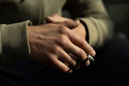 Hand in detail. Cigarette sandwiched between packs. Light on back of brush.の写真素材