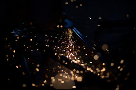 Sparks in dark. Metal grinding lights. Details of grinder's work. Small sparks fly in different directions on black background.の写真素材