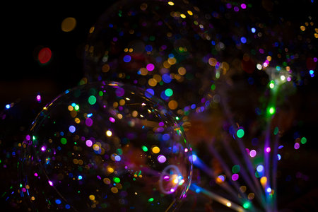 Colored balls with light bulbs inside on dark background. Texture of lights in dark. Details of holiday. Christmas decoration. Bright background for Christmas.の写真素材