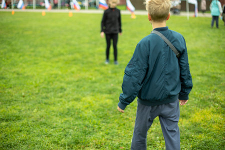 Child on green grass. Schoolboy plays on lawn in summer. Active holidays. child from behind.の写真素材