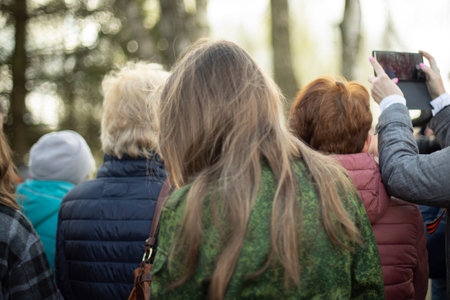 Girl with long hair. woman at ceremony. People are standing in line. Lot of people from behind.
