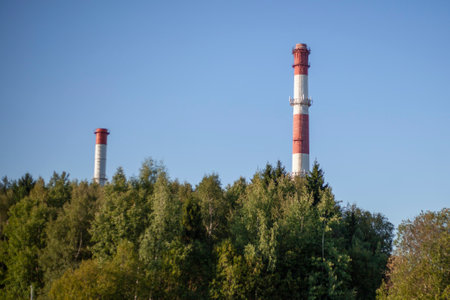 Pipes of plant over forest. industrial facility. Boiler house in city. Factory with pipes against sky.の写真素材