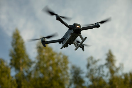 Drone flies low. Drone flight in sky. Technology of flight and shooting from sky. Device with propeller. combat drone.の写真素材