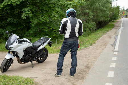 Motorcyclist is standing on the road. sports bike. Man in helmet. Details of traveling on motorcycle.の写真素材