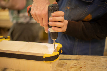 Hand holding box. Guy creates box out of wood. Work in workshop. wood processing. fixing template.の写真素材