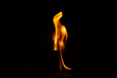 Flames in dark. Tongue of fire one. Alcohol flame retardation. Yellow glow on black background.の写真素材